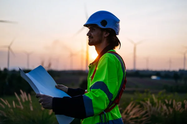 風力タービン分野でチームワークを発揮するプロのエンジニア クリーンエネルギーで働くメンテナンスワーカーのシルエットビュー 緑の生態系発電風力 — ストック写真