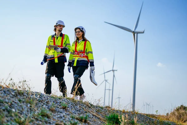 Engineers technicians team with safety uniform working at wind turbine field, Environmental engineer researching and developing clean energy sources, Green ecological power energy