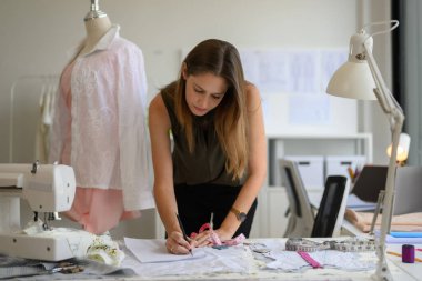 Atölyede çalışan güzel kadın terzi, kadın terzi ölçü ve kıyafet provaları, manken giyimi atölyesinde terzilik, küçük işletme sahibi.