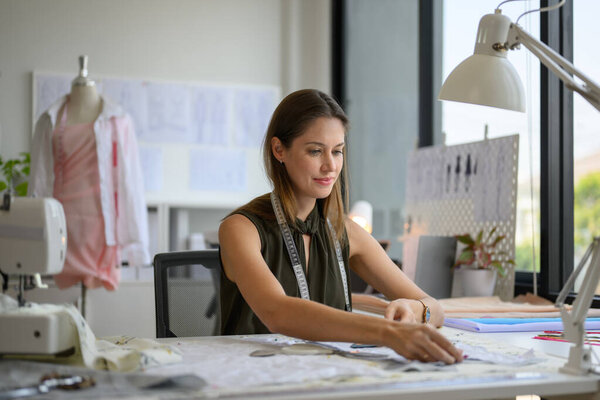 Beautiful woman dressmaker working in workshop, Female tailor fashion designer checking measurements and fitting of dress, Tailoring clothing on mannequin garment workshop studio, Small business owner