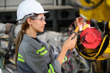 Fabrikada robot makine otomasyonuyla çalışan bakım mühendisi, endüstride akıllı teknolojili kadın teknisyen, robot makinenin parçalarını kontrol eden ve kontrol eden kadın işçi.