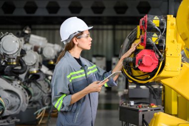 Fabrikada robot makine otomasyonuyla çalışan bakım mühendisi, endüstride akıllı teknolojili kadın teknisyen, robot makinenin parçalarını kontrol eden ve kontrol eden kadın işçi.