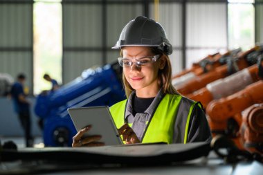Fabrikada robot makine otomasyonuyla çalışan bakım mühendisi, endüstride akıllı teknolojili kadın teknisyen, robot makinenin parçalarını kontrol eden ve kontrol eden kadın işçi.