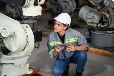 Fabrikada robot makine otomasyonuyla çalışan bakım mühendisi, endüstride akıllı teknolojili kadın teknisyen, robot makinenin parçalarını kontrol eden ve kontrol eden kadın işçi.