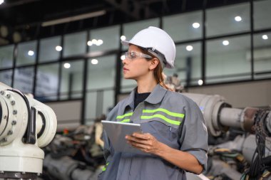Fabrikada robot makine otomasyonuyla çalışan bakım mühendisi, endüstride akıllı teknolojili kadın teknisyen, robot makinenin parçalarını kontrol eden ve kontrol eden kadın işçi.