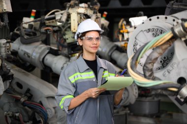 Fabrikada robot makine otomasyonuyla çalışan bakım mühendisi, endüstride akıllı teknolojili kadın teknisyen, robot makinenin parçalarını kontrol eden ve kontrol eden kadın işçi.