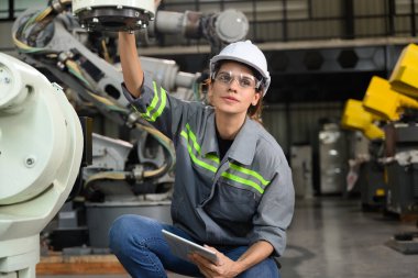 Fabrikada robot makine otomasyonuyla çalışan bakım mühendisi, endüstride akıllı teknolojili kadın teknisyen, robot makinenin parçalarını kontrol eden ve kontrol eden kadın işçi.
