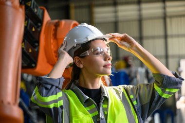 Fabrikada robot makine otomasyonuyla çalışan bakım mühendisi, endüstride akıllı teknolojili kadın teknisyen, robot makinenin parçalarını kontrol eden ve kontrol eden kadın işçi.