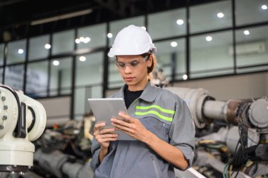 Fabrikada robot makine otomasyonuyla çalışan bakım mühendisi, endüstride akıllı teknolojili kadın teknisyen, robot makinenin parçalarını kontrol eden ve kontrol eden kadın işçi.