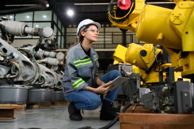 Fabrikada robot makine otomasyonuyla çalışan bakım mühendisi, endüstride akıllı teknolojili kadın teknisyen, robot makinenin parçalarını kontrol eden ve kontrol eden kadın işçi.