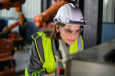Fabrikada robot makine otomasyonuyla çalışan bakım mühendisi, endüstride akıllı teknolojili kadın teknisyen, robot makinenin parçalarını kontrol eden ve kontrol eden kadın işçi.