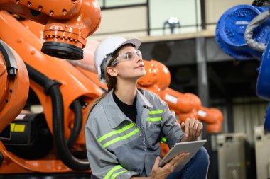 Fabrikada robot makine otomasyonuyla çalışan bakım mühendisi, endüstride akıllı teknolojili kadın teknisyen, robot makinenin parçalarını kontrol eden ve kontrol eden kadın işçi.