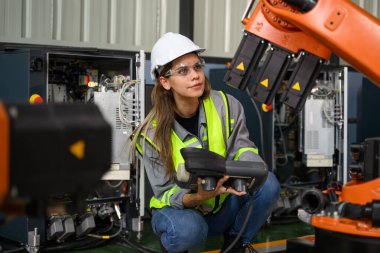 Fabrikada robot makine otomasyonuyla çalışan bakım mühendisi, endüstride akıllı teknolojili kadın teknisyen, robot makinenin parçalarını kontrol eden ve kontrol eden kadın işçi.
