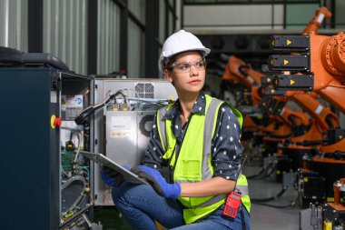 Endüstriyel fabrikada çalışan kendine güvenen kadın işyeri mühendisi, otomasyon teknolojisi fabrikasında robot makineleri kontrol eden kadın mühendis.