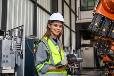 Fabrikada robot makine otomasyonuyla çalışan bakım mühendisi, endüstride akıllı teknolojili kadın teknisyen, robot makinenin parçalarını kontrol eden ve kontrol eden kadın işçi.