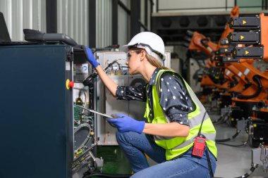 Endüstriyel fabrikada çalışan kendine güvenen kadın işyeri mühendisi, otomasyon teknolojisi fabrikasında robot makineleri kontrol eden kadın mühendis.