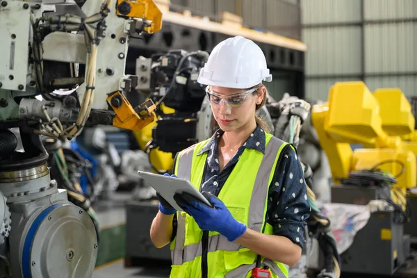 Confident female business owner engineer managing and checking work at industrial factory, Female engineer manager controlling robotic machine at automation technology factory