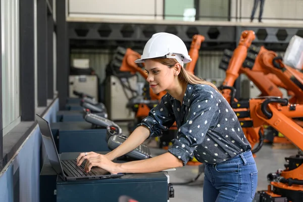 Confident female business owner engineer managing and checking work at industrial factory, Female engineer manager controlling robotic machine at automation technology factory