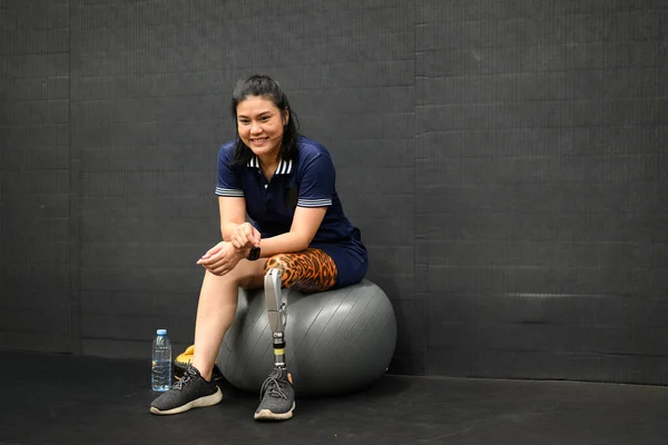 Smiling portrait of disabled athlete woman with prosthetic leg doing exercise at gym, People with physical disability, Technology with human life, New artificial limb for disabled people