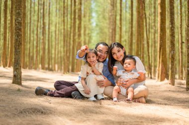 Mutlu bir aile hafta sonu parkta birlikte eğleniyor, anne ve baba parkta piknik yapıyor, anne ve baba kız ve oğulla geziyor, aile sağlıklı bir yaşam tarzına sahip.