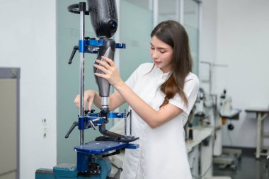 Protez bacak kontrolü yapan ve laboratuvarda çalışan genç bayan teknisyen, protez üretiminde yüksek teknoloji uzmanı, engelliler için yeni yapay uzuv üretimi