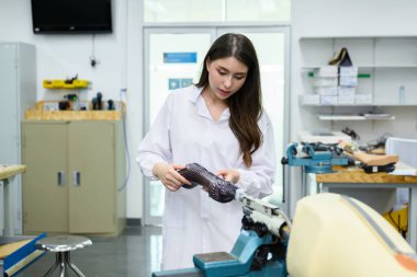 Modern protez bacağın parçalarını birleştiren ve onaran kadın teknisyen, protez bacağı tutan protez teknisyen, laboratuarda kontrol ve kontrol kalitesi, yeni yapay uzuv üretimi