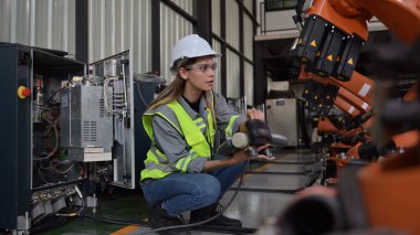 Fabrikada robot makine otomasyonuyla çalışan bakım mühendisi, endüstride akıllı teknolojili kadın teknisyen, robot makinenin parçalarını kontrol eden ve kontrol eden kadın işçi.