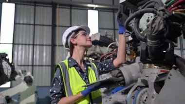 Endüstriyel fabrikada çalışan kendine güvenen kadın işyeri mühendisi, otomasyon teknolojisi fabrikasında robot makineleri kontrol eden kadın mühendis.