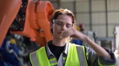 Fabrikada robot makine otomasyonuyla çalışan bakım mühendisi, endüstride akıllı teknolojili kadın teknisyen, robot makinenin parçalarını kontrol eden ve kontrol eden kadın işçi.