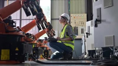 Fabrikada robot makine otomasyonuyla çalışan bakım mühendisi, endüstride akıllı teknolojili kadın teknisyen, robot makinenin parçalarını kontrol eden ve kontrol eden kadın işçi.