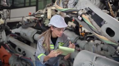 Fabrikada robot makine otomasyonuyla çalışan bakım mühendisi, endüstride akıllı teknolojili kadın teknisyen, robot makinenin parçalarını kontrol eden ve kontrol eden kadın işçi.