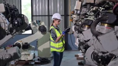 Endüstriyel fabrikada çalışan kendine güvenen kadın işyeri mühendisi, otomasyon teknolojisi fabrikasında robot makineleri kontrol eden kadın mühendis.