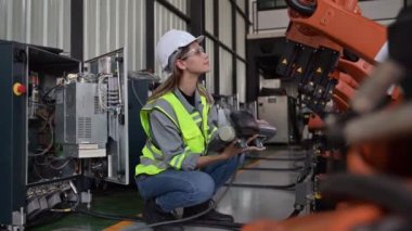 Fabrikada robot makine otomasyonuyla çalışan bakım mühendisi, endüstride akıllı teknolojili kadın teknisyen, robot makinenin parçalarını kontrol eden ve kontrol eden kadın işçi.