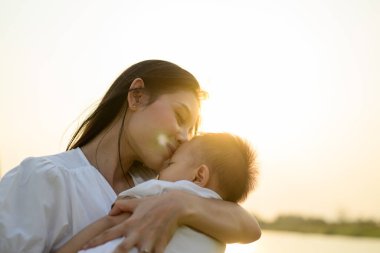 Sevgi dolu bir anne yeni doğan bebeğini parkta kucağında taşır, mutlu bir aile hafta sonu parkta dinlenir ve eğlenir neşeli anne ve çocuklar parkta pikniğin tadını çıkarırlar.