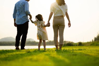 Mutlu bir aile hafta sonu parkta dinleniyor, baba ve kız parkta piknik yapıyor, ebeveynler kızlarıyla seyahat ediyor, mutlu bir aile hayatı sürüyor. 