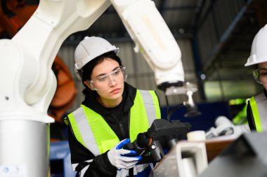 Endüstriyel fabrikada robot silahlarla çalışan birkaç mutlu kadın mühendis makine bakımını kontrol eden teknisyenler, akıllı endüstriyel mühendisler...
