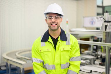 Fabrikadaki makine ve ekipmanları kontrol etmek için terminal güç kablo ekipmanlarıyla çalışan elektrikçi portresi, endüstriyel fabrikadaki robot makinenin parçalarını kontrol eden ve tamir eden teknisyenler