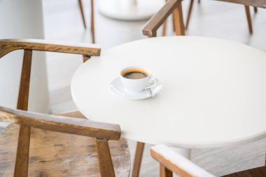 Kahve dükkanında beyaz masaya izole edilmiş beyaz kahve, masada sıcak kahve, kafeteryada kahve fincanı.