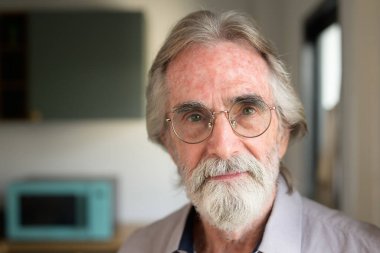 Gözlüklü mutlu son sınıf öğrencisi, kamera fotoğrafına bakıyor büyükbaba evde dinleniyor ve dinleniyor, mutlu emekli adam evde.