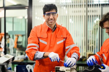 Endüstriyel santralde programlama kurmak için makine üzerinde çalışan ve çözen mühendisler, teknisyenler fabrika, teknoloji ve yenilikteki robotik makinelerin parçalarını kontrol edip onarıyorlar