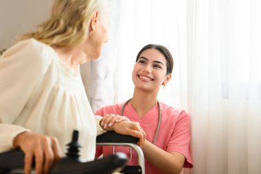 Ev ziyaretinde yaşlı bir hastayla konuşan mutlu bir doktor, evde ya da huzurevinde yaşlı bir hastayla ilgilenen bir doktor ya da hemşire, steteskoplu profesyonel bir kadın doktor,