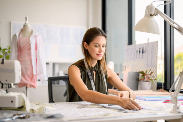 Happy female dressmaker working in workshop, Female tailor fashion designer checking measurements and fitting of dress, Tailoring clothing on mannequin garment workshop studio, Small business owner