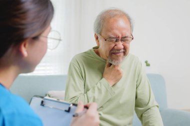 Young doctor examining senior patient at home visit, Senior man consulting medicine with pharmacist, Caregiver nurse taking care of elderly grandfather sitting on sofa at home, Medical service concept