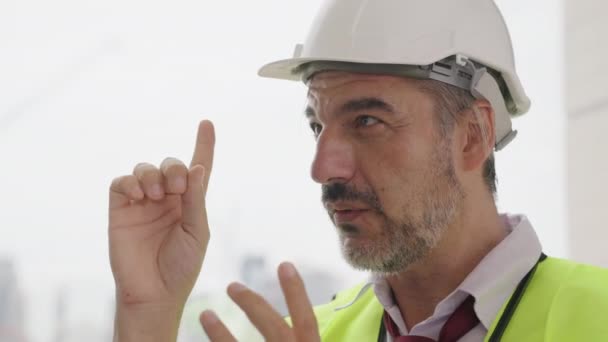 建設現場で働く安全ベストを持つ幸せな土木技術者のフォアマンの肖像 労働者チームと話を構築する上で働く男性請負業者 — ストック動画