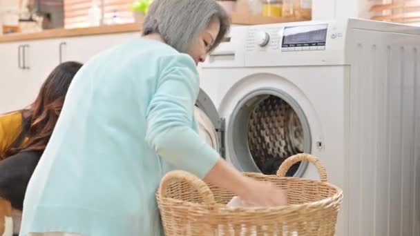 大妈在家洗衣服 大妈把衣服放在洗衣机前 亚洲家庭主妇做家务活 — 图库视频影像