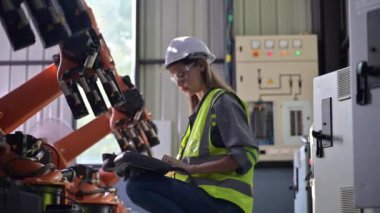Fabrikada robot makine otomasyonuyla çalışan bakım mühendisi, endüstride akıllı teknolojili kadın teknisyen, robot makinenin parçalarını kontrol eden ve kontrol eden kadın işçi.