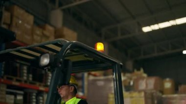 Fabrikada forklift üzerinde çalışan depo işçisi, sarı miğfer takan forklift şoförü, depoda çalışan forklift şoförü, endüstriyel mühendislik işçisi.