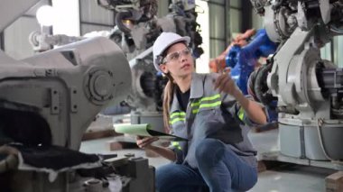 Fabrikada robot makine otomasyonuyla çalışan bakım mühendisi, endüstride akıllı teknolojili kadın teknisyen, robot makinenin parçalarını kontrol eden ve kontrol eden kadın işçi.