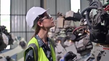 Endüstriyel fabrikada çalışan kendine güvenen kadın işyeri mühendisi, otomasyon teknolojisi fabrikasında robot makineleri kontrol eden kadın mühendis.