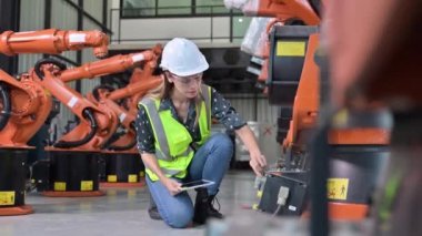 Endüstriyel fabrikada çalışan kendine güvenen kadın işyeri mühendisi, otomasyon teknolojisi fabrikasında robot makineleri kontrol eden kadın mühendis.